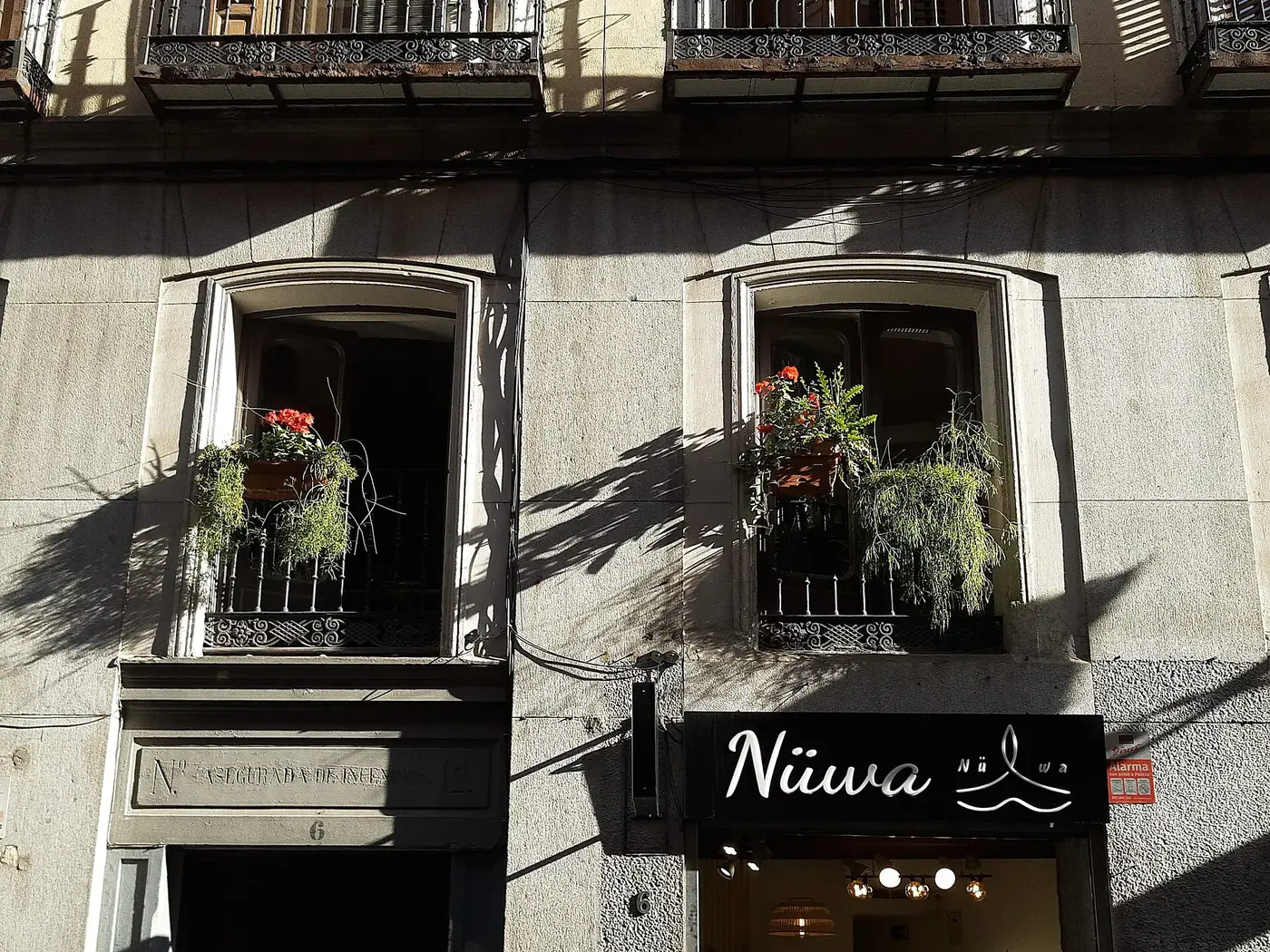 Jardineras con flores en los balcones de un edificio de piedra del centro de Madrid